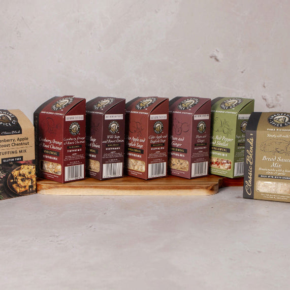 A selection of packaged food products from Shropshire Spice Company displayed on a wooden board, including bread sauce.