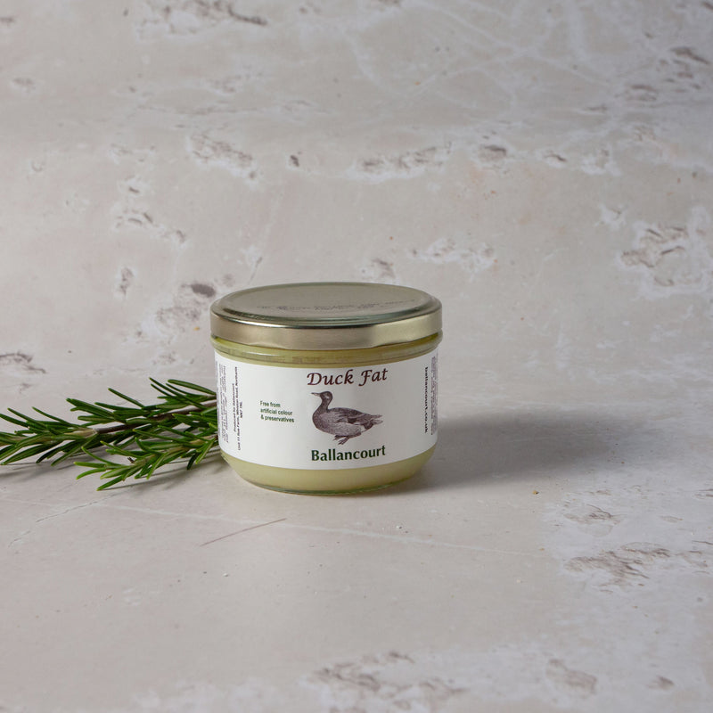 A jar of duck fat labeled 'Ballancourt Duck Fat' with a sprig of rosemary on a marble surface.