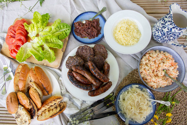 Wild boar sausages sausages and old cow burgers served with brioche buns, finger rolls, apple and carrot slaw, onions and cabbage toppings, grated gruyere cheese and fresh lettuce and tomatoes