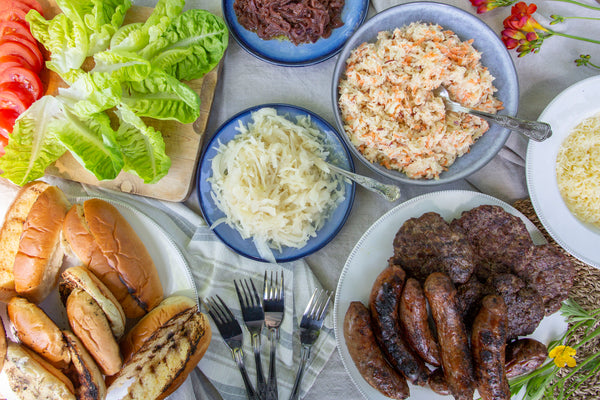 Wild boar sausages sausages and old cow burgers served with brioche buns, finger rolls, apple and carrot slaw, onions and cabbage toppings, grated gruyere cheese and fresh lettuce and tomatoes