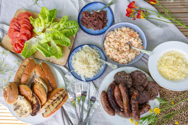 Wild boar sausages sausages and old cow burgers served with brioche buns, finger rolls, apple and carrot slaw, onions and cabbage toppings, grated gruyere cheese and fresh lettuce and tomatoes