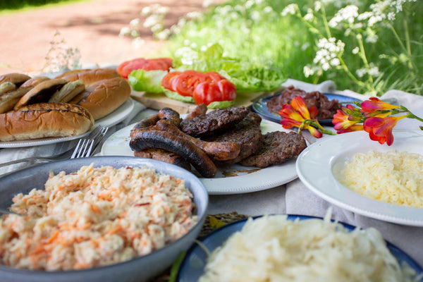 Gloucester Old Spot Sausages sausages and old cow burgers served with brioche buns, finger rolls, apple and carrot slaw, onions and cabbage toppings, grated gruyere cheese and fresh lettuce and tomatoes