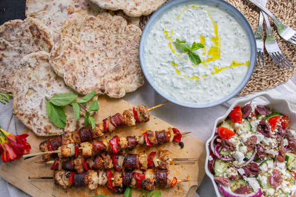 Chicken kebabs with white onion and Romano red peppers with flatbreads, tzatziki and Greek salad